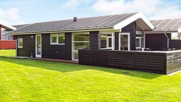 A modern two-story house with a flat roof, large windows, and a well-maintained lawn.