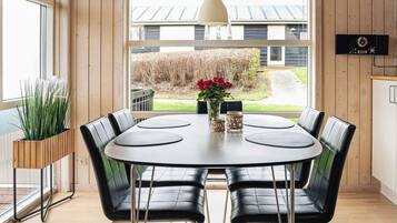 A dining area with a round table, black chairs, and a vase with red flowers.