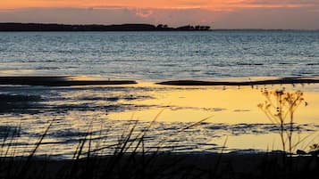 Un atardecer sobre una superficie de agua tranquila con una costa lejana.