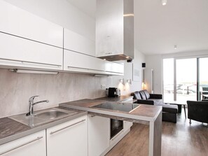Une cuisine moderne avec des meubles blancs, un évier en acier inoxydable et une cuisinière intégrée.