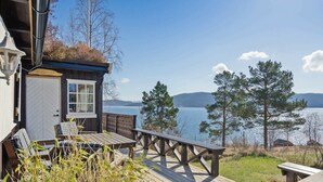 Eine Holzterrasse mit Sitzgelegenheit im Freien, mit Blick auf einen See und Berge.