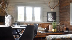 Ein gemütliches Blockhaus-Interieur mit Essbereich, einer Couch und einem Kamin.