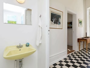 A bathroom with a yellow sink, a mirror, and a framed picture on the wall.
