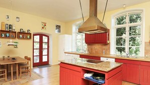 A kitchen with red cabinets, a granite countertop, and a built-in stove. - Vintage Holiday Home in Syddanmark With Private Whirlpool (Sydlangeland)