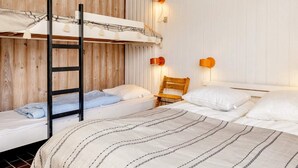Habitación con literas, dos mesitas de noche y dos lámparas fijadas a la pared.