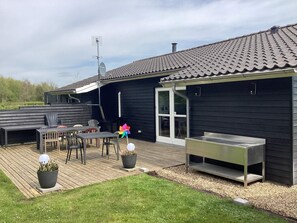 Eine Terrasse mit Gartenmöbeln, einem Grill und einer Windmühle.