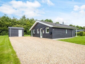 Ein modernes, zweistöckiges Haus mit einem Schotterweg, einer Garage und einem gepflegten Rasen.