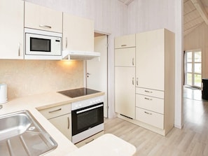 A modern kitchen with a built-in oven, microwave, and a stainless steel sink. - Holiday Home in GrÃ¶mmitz (Groemitz)