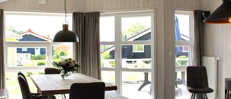 A modern interior with a dining area, large windows, and a fireplace.