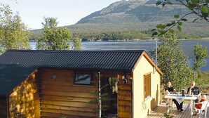 Une cabane en bois avec un toit en métal, une terrasse et une table avec des chaises.
