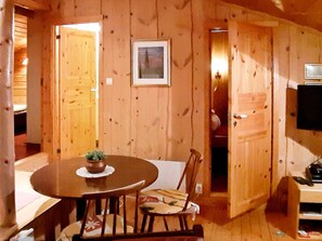 A wooden interior with a dining table, chairs, and a television.