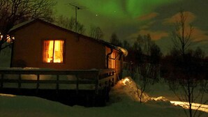 A cabin with a visible window, a snow-covered ground, and a clear night sky. - 5 Person Holiday Home in Straumsbukta (Tromsø)
