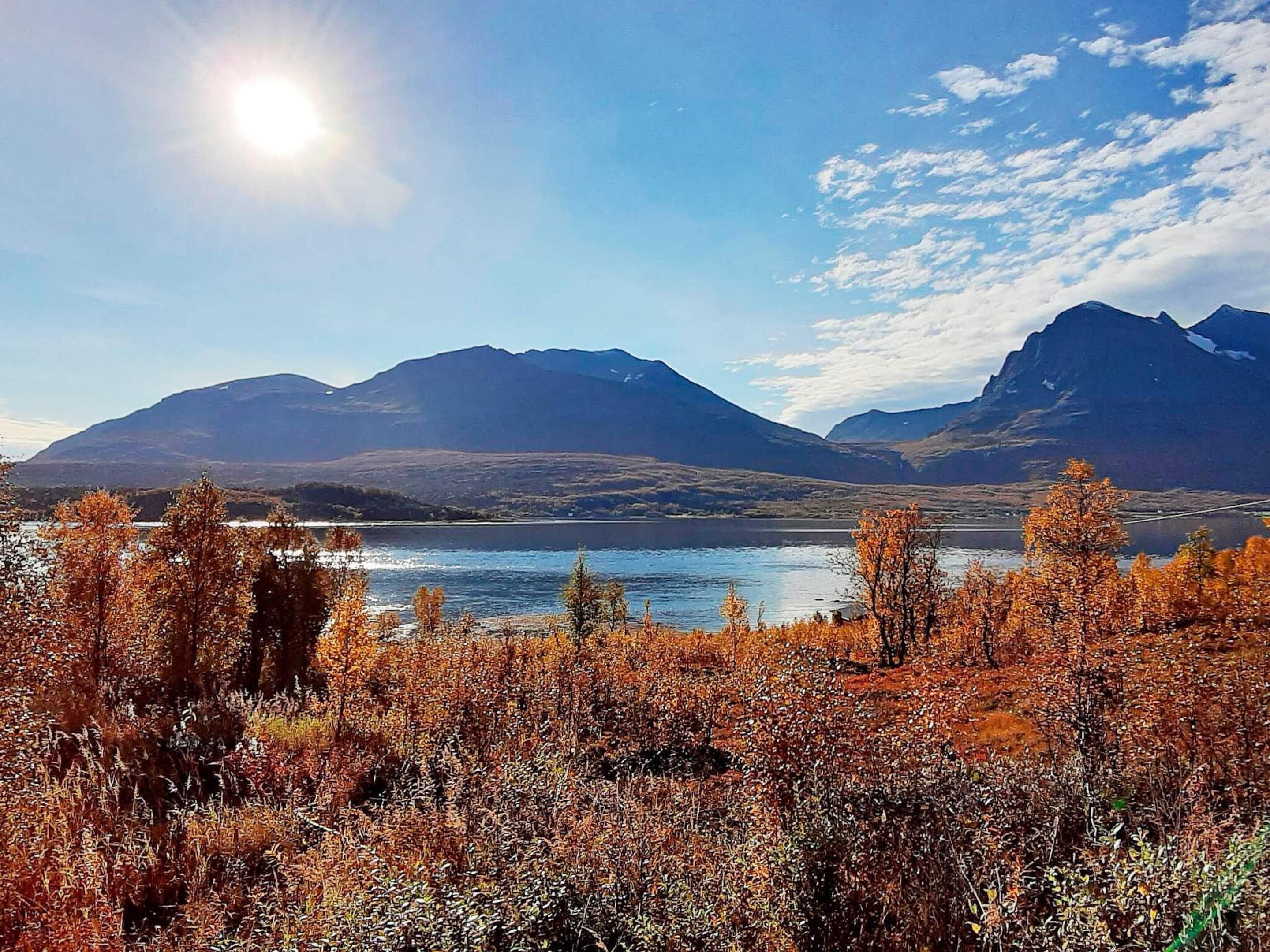 A mountainous landscape with a lake and autumn foliage.