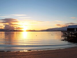 Un atardecer sobre una superficie de agua tranquila con un muelle de madera que se adentra en el agua.