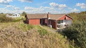 A red building with a chimney, a white building in the background, and a grassy field. - Vibrant Holiday Home in RÃ¸mÃ¸ near Sea (Rømø)