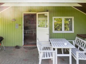 A covered outdoor area with a table and benches, a door leading to an interior space, and a window with a view of greenery. - 4 Person Holiday Home in Grindsted-by Traum (Grindsted)