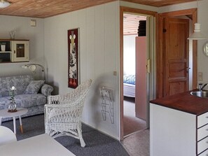 A room with a white wicker chair, a white sofa, a small table with a glass, and a door leading to another room. - 4 Person Holiday Home in Grindsted-by Traum (Grindsted)