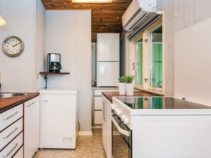A compact kitchen with a refrigerator, microwave, coffee maker, and a washing machine. - 4 Person Holiday Home in Grindsted-by Traum (Grindsted)