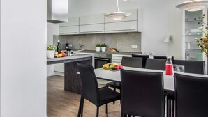 Een moderne keuken met een centraal eiland, zwarte stoelen en een eettafel.