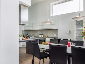 A modern kitchen with a central island, black chairs, and a dining table. - Holiday Home in Wendtorf (Schönberg)