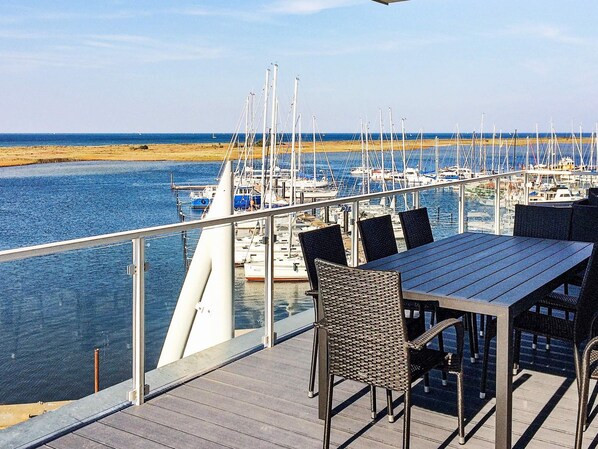 A deck with a table and chairs overlooking a marina with boats.