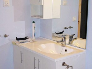 A bathroom with a double sink, a mirror, and a cabinet. - 6 Person Holiday Home in Alsvag (Oksnes)