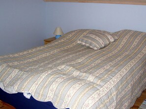 A bed with a striped bedspread, a pillow, and a bedside lamp on a wooden nightstand. - 6 Person Holiday Home in Alsvag (Oksnes)