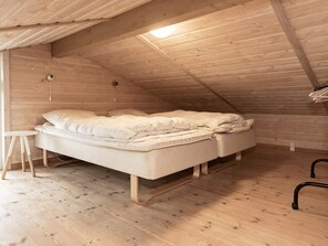 A single bed in a room with wooden walls and flooring, a small table, and a hanging light fixture. - 5 Star Holiday Home in Thisted (Thisted)
