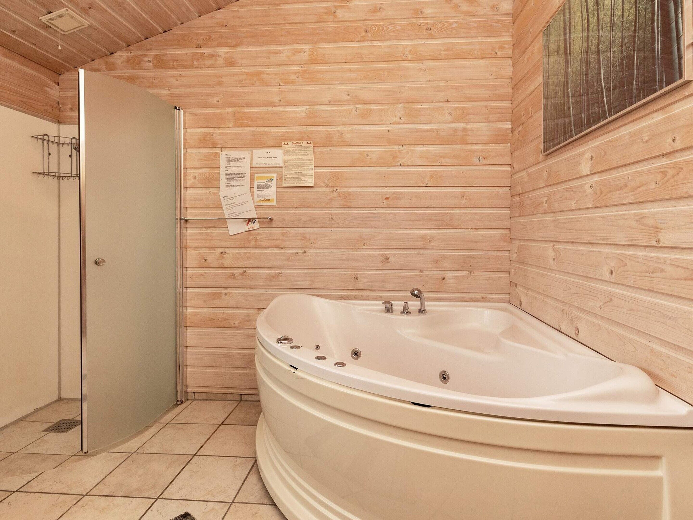 Baño de cabaña de madera con una bañera independiente, ducha y puerta.