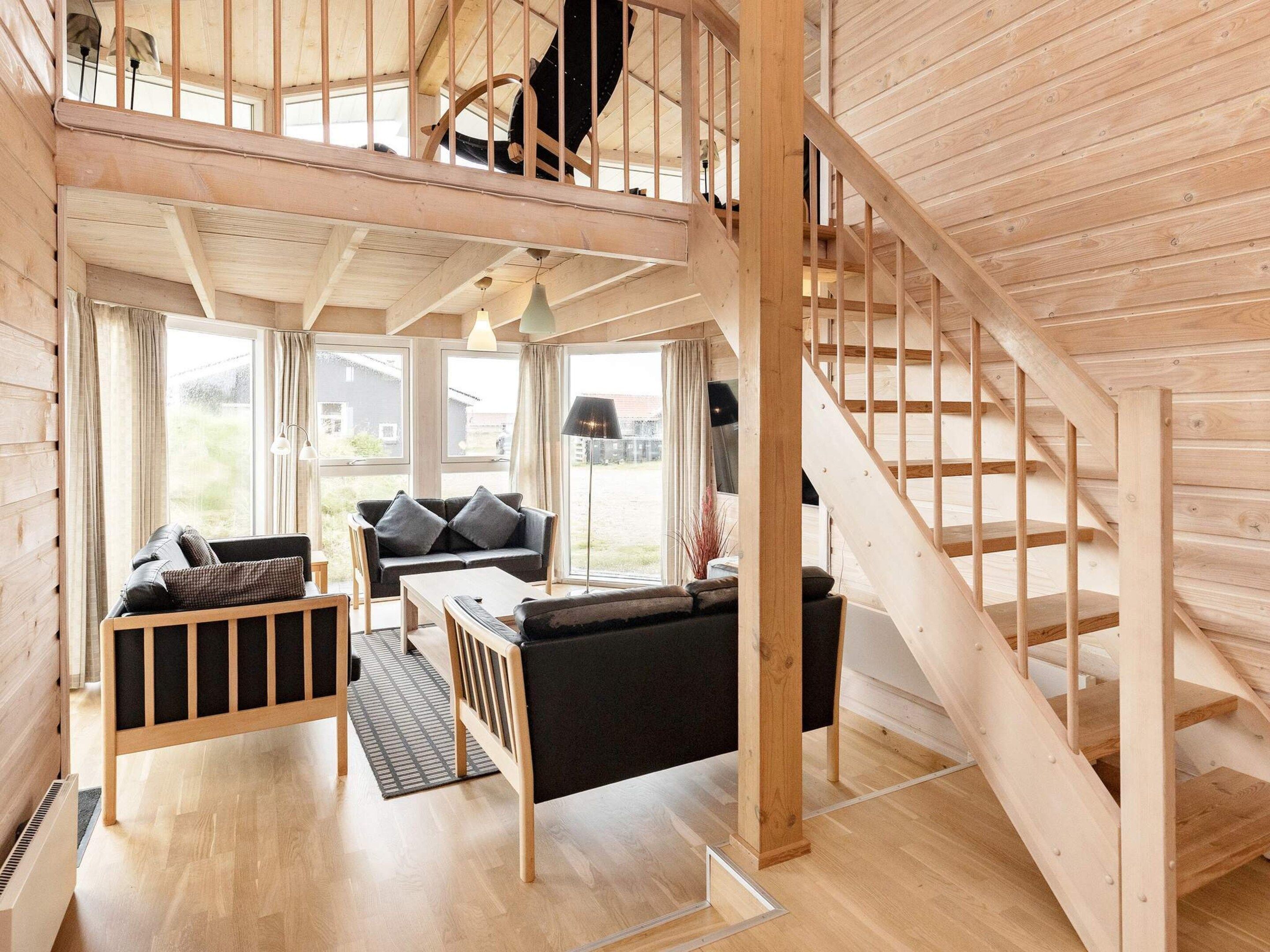 Et træinteriør med trappe, sofa, bord og fjernsyn.