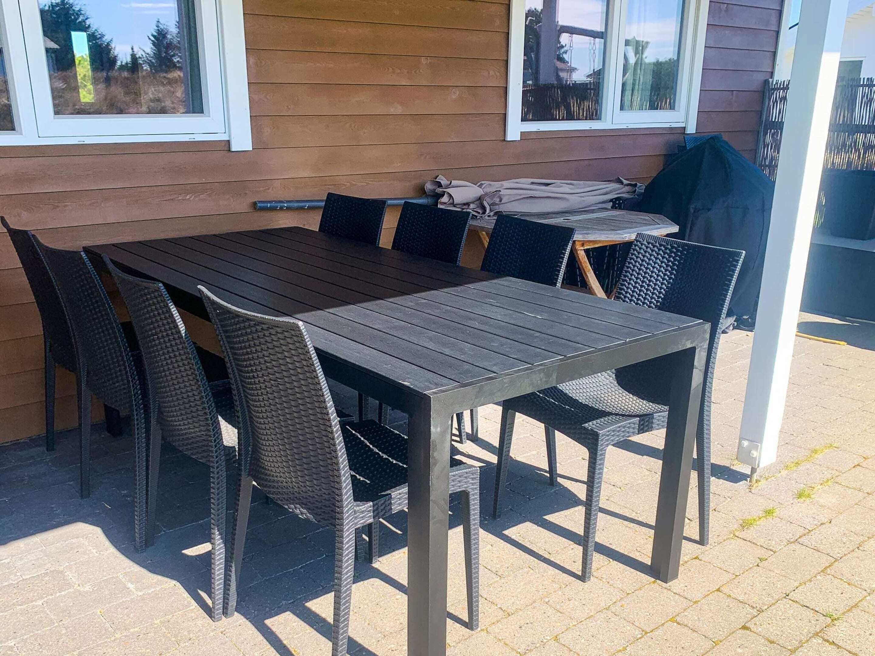 An outdoor patio with a wooden table and wicker chairs.