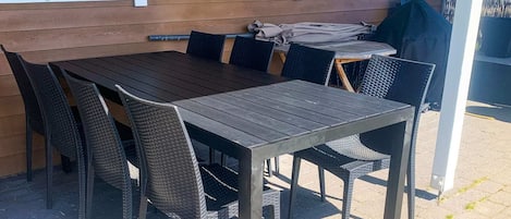 An outdoor patio with a wooden table and wicker chairs.