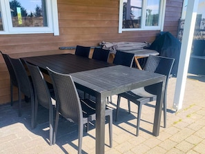 An outdoor patio with a wooden table and wicker chairs. - 5 Star Holiday Home in Thisted (Thisted)