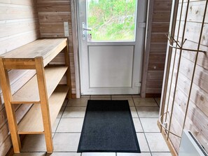A wooden interior with a door, a bench, and a doormat.