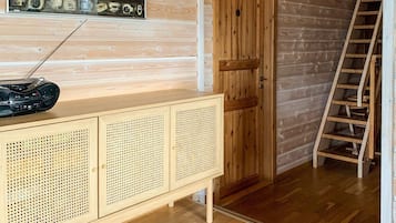 Un interior de madera con una puerta de madera, una escalera, un armario con paneles perforados y una radio encima.