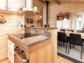 A modern kitchen with a central island, wooden cabinets, and a dining area with chairs.