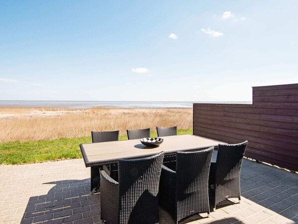 Une terrasse avec une table et des chaises, donnant sur une plage.