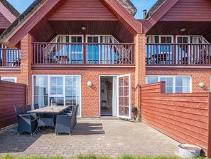 A two-story building with a patio area featuring a table and chairs. - 5 Star Holiday Home in Romo (Rømø)