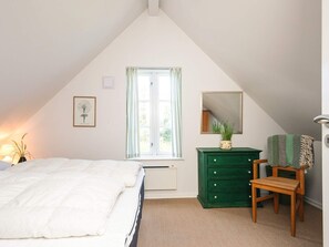 A bedroom with a bed, a dresser, a chair, a window, and a radiator.