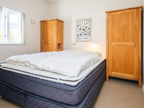 A bedroom with a bed, two wooden wardrobes, a wall-mounted picture, and a window with curtains. - 5 Star Holiday Home in Blavand (Blavand)