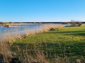 A grassy area with a picnic table and a body of water. - 5 Star Holiday Home in Blavand (Blavand)