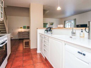 A modern kitchen with white cabinetry, a built-in oven, and a tiled floor.