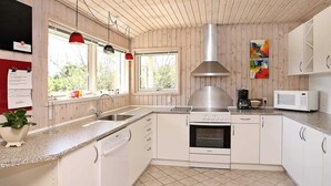 Eine moderne Küche mit Holzwänden, einer Edelstahl-Dunstabzugshaube, einer Mikrowelle und einem Geschirrspüler.