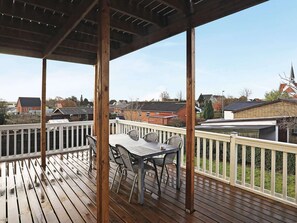 A wooden deck with a table and chairs, surrounded by a white railing, overlooking a residential area. - 10 Person Holiday Home in Bagenkop (Sydlangeland)