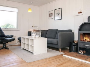 A modern living room with a grey sofa, a white coffee table, a black chair, a fireplace, and two framed artworks on the wall.