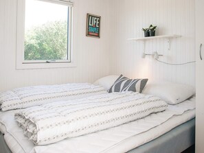 Un dormitorio con cama, ventana, estante de pared con plantas y un cartel motivacional.