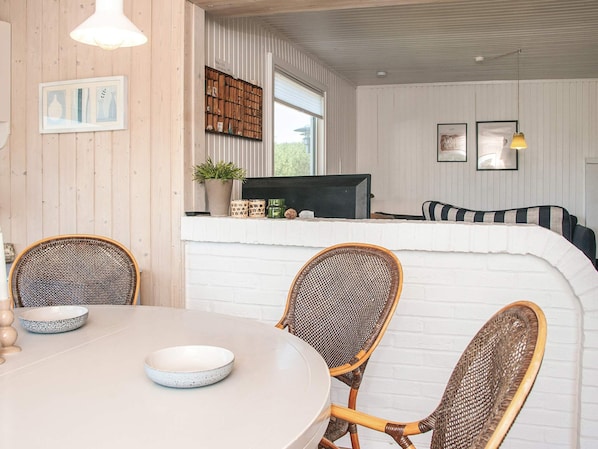 A dining area with a round table, wicker chairs, and a white brick wall.