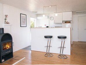 Una cocina moderna con una isla central, dos taburetes de bar, un horno empotrado y un reloj a la vista.