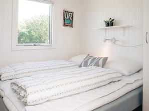 A bedroom with a bed, a window, a wall-mounted shelf with plants, and a motivational poster. - 6 Person Holiday Home in Ringkobing (Ringkobing)