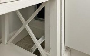 Um quarto branco com janela, porta e chão visível.